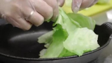 Yunan salatası nın hazırlanması sırasında marulların küçük parçalarhalinde yırtılması.