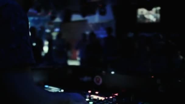 Диджей за пультом смешивает музыку в ночном танцевальном клубе . — стоковое видео