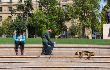Santiago, Şili - 6 Nisan 2018. Yakın bir köpek uyurken iki kişi bir Park adımlar üzerinde oturuyorsun. Yalnızca içerik kullanımı.
