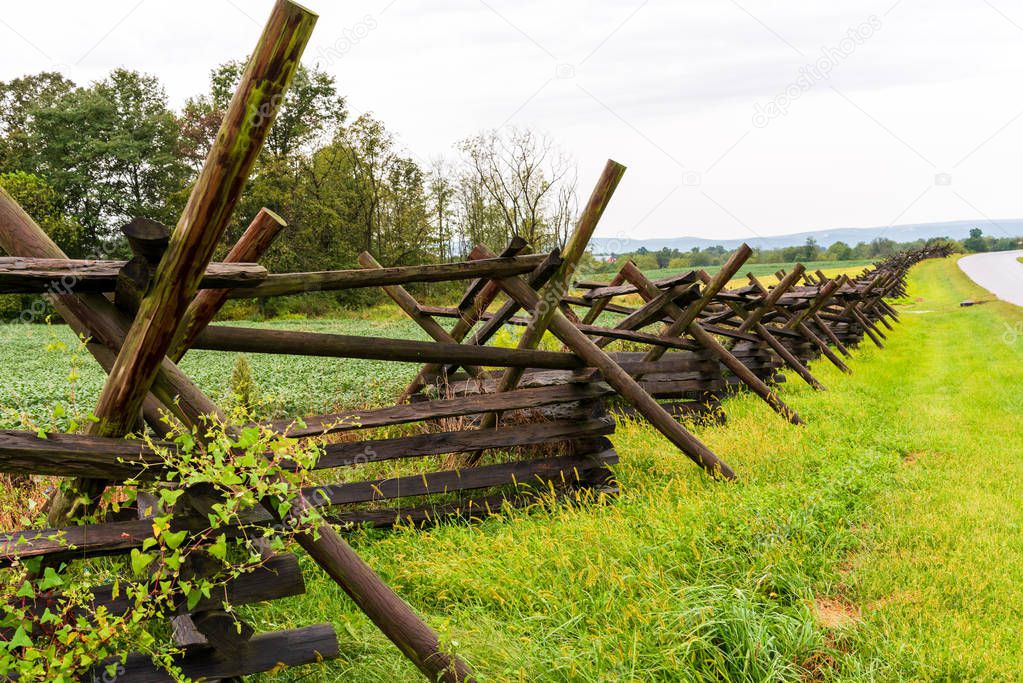A long woodedn fence that serves as a fortification lines a historic Gettysburg battlefield.