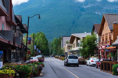 Banff, Alberta, Kanada -- 5 Ağustos 2018. Banff 'taki ana alışveriş caddesinden bir araba geçiyor; dağlar tam önümüzde..