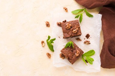 Brownie tatlı çikolata tatlı ceviz ve demek yapraklarla kopya alanı üzerinde pastel bej arka plan - beyaz kağıt üzerinde güzel afiş lezzetli kahverengi Kakaolu pasta pişmiş..