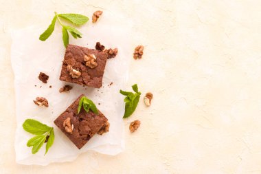 Brownie tatlı çikolata tatlı ceviz ve demek yapraklarla kopya alanı üzerinde pastel bej arka plan - beyaz kağıt üzerinde güzel afiş lezzetli kahverengi Kakaolu pasta pişmiş..
