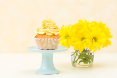 Cupcake standı ve pastel arka plan üzerinde cam vazoda papatya buketi ihale sarı krem dekorasyonu ile. Tatlı tatlı tebrik kartı için pişmiş.