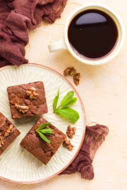 Brownie tatlı çikolata tatlı ceviz ve zanaat plaka ve pastel bej arka plan - lezzetli kahverengi pişmiş pasta ile güzel afiş üzerinde siyah kahve demek yapraklarda.
