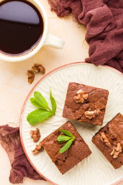 Brownie tatlı çikolata tatlı ceviz ve zanaat plaka ve pastel bej arka plan - lezzetli kahverengi pişmiş pasta ile güzel afiş üzerinde siyah kahve demek yapraklarda.