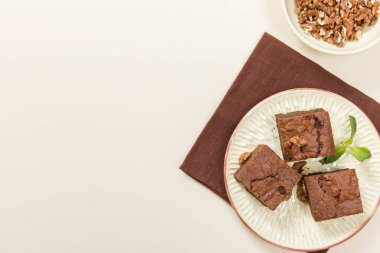 Brownie tatlı çikolata tatlı ceviz ve zanaat plaka üzerinde demek yaprakları ile kopya alanı üzerinde pastel bej arka plan - güzel afiş lezzetli kahverengi Kakaolu pasta pişmiş..