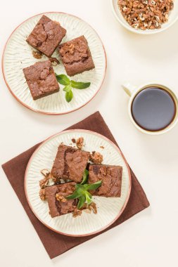 Brownie tatlı çikolata tatlı ceviz ve zanaat plaka ve pastel bej arka plan - lezzetli kahverengi pişmiş pasta ile güzel afiş üzerinde siyah kahve demek yapraklarda.