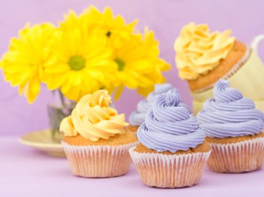 Top kek tatlı sarı ve mor krem ve Kasımpatı Menekşe pastel zemin üzerine süslenmiş. Boşaltmak alan. Tebrik için kullanılabilir anneler gün ve Sevgililer kartı. Minimalizm kavramı.