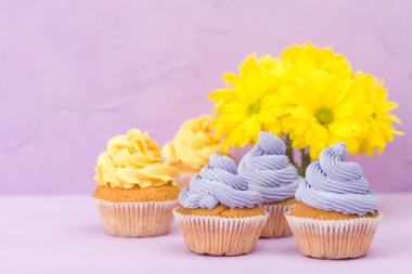 Top kek tatlı sarı ve mor krem ve Kasımpatı Menekşe pastel zemin üzerine süslenmiş. Boşaltmak alan. Tebrik için kullanılabilir anneler gün ve Sevgililer kartı. Minimalizm kavramı.