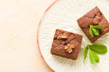 Brownie tatlı çikolata tatlı ceviz ve zanaat plaka üzerinde demek yaprakları ile kopya alanı üzerinde pastel bej arka plan - güzel afiş lezzetli kahverengi Kakaolu pasta pişmiş..