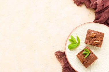 Brownie tatlı çikolata tatlı ceviz ve zanaat plaka üzerinde demek yaprakları ile kopya alanı üzerinde pastel bej arka plan - güzel afiş lezzetli kahverengi Kakaolu pasta pişmiş..