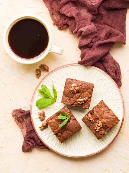 Brownie tatlı çikolata tatlı ceviz ve zanaat plaka ve pastel bej arka plan - lezzetli kahverengi pişmiş pasta ile güzel afiş üzerinde siyah kahve demek yapraklarda.