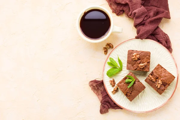 Brownie tatlı çikolata tatlı ceviz ve zanaat plaka ve siyah kahve demek yapraklarda pastel bej arka plan - lezzetli kahverengi pişmiş pasta ile güzel afiş üzerinde kopya alanı ile.