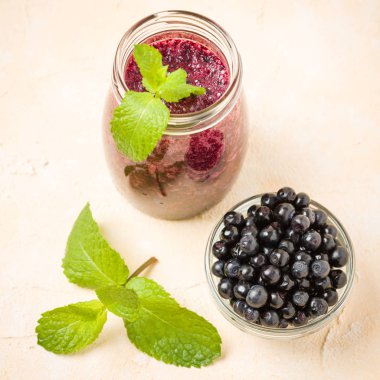 Yaban mersini taze yüzlü olgun vahşi orman meyveleri ve yeşil nane yaprakları ile.