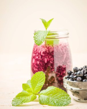 Olgun vahşi orman meyveleri ve yeşil nane yaprakları ile ham blueberry smoothie.