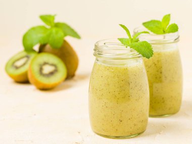 Taze yeşil nane yaprakları ve ham olgun kesilmiş meyve karışık vitamini sağlıklı gıda kavramı için kokteyl şeffaf kavanoz sarı pastel arka planda - kivi smoothie süslenmiş.
