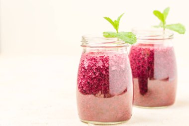 Taze yeşil nane ile dekore edilmiş blueberry smoothie sarı pastel özgeçmişlerine - yaz karma vitamini şeffaf kavanoz kokteyl bırakır. Berry shaked suyu sağlıklı gıda konsepti için.