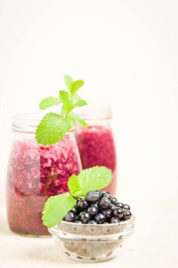 Blueberry smoothie yakın fotoğraf yaz karışımlı vitamin kokteyl ile kadar taze yeşil nane yaprakları ve sağlıklı yaşam konsepti için sarı pastel arka plan üzerinde ham Olgun meyveleri süslenmiş.