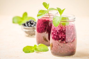 Taze yeşil nane yaprakları ve ham Olgun meyveleri yaz karışımlı vitamini kopya alanı ile kokteyl şeffaf kavanoz sarı pastel arka planda - Blueberry smoothie süslenmiş.