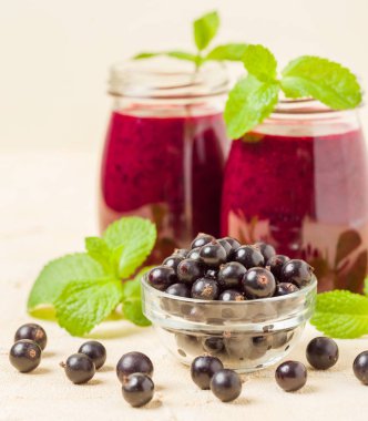 Taze yeşil nane yaprakları ve ham Olgun meyveleri yaz karışımlı vitamini sağlıklı gıda kavramı için kokteyl şeffaf kavanoz sarı pastel arka planda - frenk üzümü güler yüzlü süslenmiş.