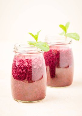 Blueberry smoothie sarı pastel zemin üzerine Yeşil taze nane yaprakları ile süslenmiş. Yaz Karma vitamini kokteyl - şeffaf kavanoz berry shaked suyu sağlıklı gıda konsepti için.