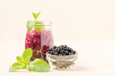 Taze yeşil nane yaprakları ve ham Olgun meyveleri yaz karışımlı vitamini kopya alanı ile kokteyl şeffaf kavanoz sarı pastel arka planda - Blueberry smoothie süslenmiş.