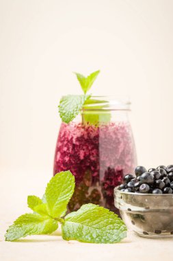 Taze yeşil nane yaprakları ve ham Olgun meyveleri yaz karışımlı vitamini kopya alanı ile kokteyl şeffaf kavanoz sarı pastel arka planda - Blueberry smoothie süslenmiş.