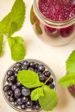 Taze yeşil nane yaprakları ve ham Olgun meyveleri yaz karışımlı vitamini kopya alanı ile kokteyl şeffaf kavanoz sarı pastel arka planda - Blueberry smoothie süslenmiş.