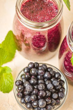 Taze yeşil nane yaprakları ve ham Olgun meyveleri yaz karışımlı vitamini kopya alanı ile kokteyl şeffaf kavanoz sarı pastel arka planda - Blueberry smoothie süslenmiş.