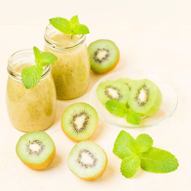Taze yeşil nane yaprakları ve ham olgun kesilmiş meyve karışık vitamini sağlıklı gıda kavramı için kokteyl şeffaf kavanoz sarı pastel arka planda - kivi smoothie süslenmiş.