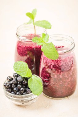 Taze yeşil nane yaprakları ve ham Olgun meyveleri yaz karışımlı vitamini kopya alanı ile kokteyl şeffaf kavanoz sarı pastel arka planda - Blueberry smoothie süslenmiş.