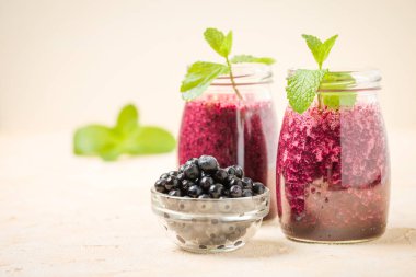 Taze yeşil nane yaprakları ve ham Olgun meyveleri yaz karışımlı vitamini kopya alanı ile kokteyl şeffaf kavanoz sarı pastel arka planda - Blueberry smoothie süslenmiş.
