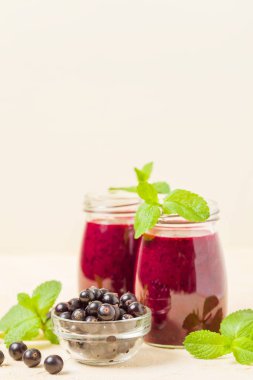 Taze yeşil nane yaprakları ve ham Olgun meyveleri yaz karışımlı vitamini sağlıklı gıda kavramı için kokteyl şeffaf kavanoz sarı pastel arka planda - frenk üzümü güler yüzlü süslenmiş.