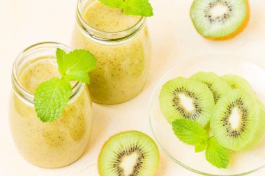 Taze yeşil nane yaprakları ve ham olgun kesilmiş meyve karışık vitamini sağlıklı gıda kavramı için kokteyl şeffaf kavanoz sarı pastel arka planda - kivi smoothie süslenmiş.