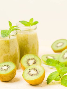 Taze yeşil nane yaprakları ve ham olgun kesilmiş meyve karışık vitamini sağlıklı gıda kavramı için kokteyl şeffaf kavanoz sarı pastel arka planda - kivi smoothie süslenmiş.