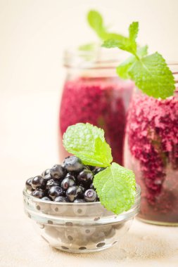 Taze yeşil nane yaprakları ve ham Olgun meyveleri yaz karışımlı vitamini kopya alanı ile kokteyl şeffaf kavanoz sarı pastel arka planda - Blueberry smoothie süslenmiş.