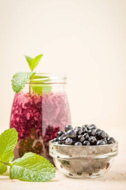 Taze yeşil nane yaprakları ve ham Olgun meyveleri yaz karışımlı vitamini kopya alanı ile kokteyl şeffaf kavanoz sarı pastel arka planda - Blueberry smoothie süslenmiş.