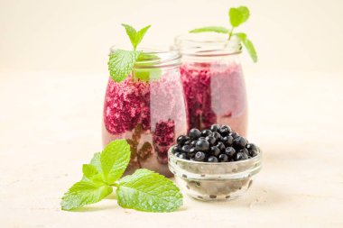 Taze yeşil nane yaprakları ve ham Olgun meyveleri yaz karışımlı vitamini kopya alanı ile kokteyl şeffaf kavanoz sarı pastel arka planda - Blueberry smoothie süslenmiş.