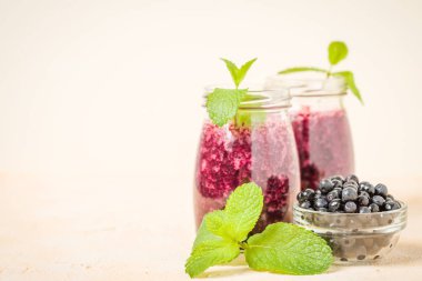 Taze yeşil nane yaprakları ve ham Olgun meyveleri yaz karışımlı vitamini kopya alanı ile kokteyl şeffaf kavanoz sarı pastel arka planda - Blueberry smoothie süslenmiş.
