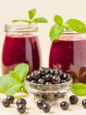 Taze yeşil nane yaprakları ve ham Olgun meyveleri yaz karışımlı vitamini sağlıklı gıda kavramı için kokteyl şeffaf kavanoz sarı pastel arka planda - frenk üzümü güler yüzlü süslenmiş.