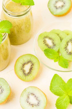 Taze yeşil nane yaprakları ve ham olgun kesilmiş meyve karışık vitamini sağlıklı gıda kavramı için kokteyl şeffaf kavanoz sarı pastel arka planda - kivi smoothie süslenmiş.