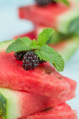 Böğürtlen ve nane yaprağı ile pasta üzerinde mavi pastel renkli - dilimlenmiş karpuz yakın çekim yaz taze çiğ olgunlaşmış meyve lezzetli vejetaryen tatlı makro fotoğrafçılık.