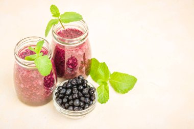 Taze yeşil nane yaprakları ve ham Olgun meyveleri yaz karışımlı vitamini kopya alanı ile kokteyl şeffaf kavanoz sarı pastel arka planda - Blueberry smoothie süslenmiş.
