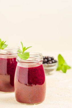 Taze yeşil nane yaprakları ve ham Olgun meyveleri yaz karışımlı vitamini sağlıklı gıda kavramı için kokteyl şeffaf kavanoz sarı pastel arka planda - frenk üzümü güler yüzlü süslenmiş.