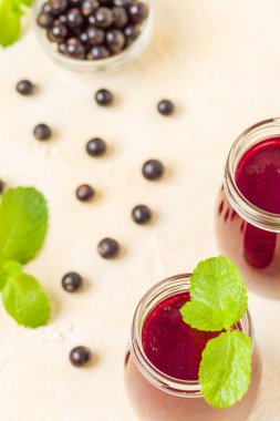 Taze yeşil nane yaprakları ve ham Olgun meyveleri yaz karışımlı vitamini sağlıklı gıda kavramı için kokteyl şeffaf kavanoz sarı pastel arka planda - frenk üzümü güler yüzlü süslenmiş.