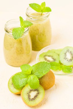Taze yeşil nane yaprakları ve ham olgun kesilmiş meyve karışık vitamini sağlıklı gıda kavramı için kokteyl şeffaf kavanoz sarı pastel arka planda - kivi smoothie süslenmiş.