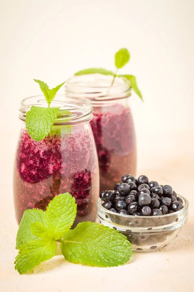 Taze yeşil nane yaprakları ve ham Olgun meyveleri yaz karışımlı vitamini kopya alanı ile kokteyl şeffaf kavanoz sarı pastel arka planda - Blueberry smoothie süslenmiş.