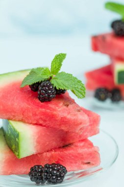 Böğürtlen ve nane yaprağı ile pasta üzerinde mavi pastel renkli - dilimlenmiş karpuz yakın çekim yaz taze çiğ olgunlaşmış meyve lezzetli vejetaryen tatlı makro fotoğrafçılık.