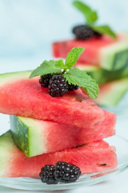 Böğürtlen ve nane yaprağı ile pasta üzerinde mavi pastel renkli - dilimlenmiş karpuz yakın çekim yaz taze çiğ olgunlaşmış meyve lezzetli vejetaryen tatlı makro fotoğrafçılık.
